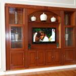 This built in Cherry wall unit is finished with our Japanese Sienna stain.  It features raised panel doors, glass doors, glass shelves, fluted columns, and a carved crown molding.  