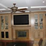This wall-to-wall entertainment center is sprayed in our beige lacquer and hand brushed in our umber glazes.  It features a granite fireplace, raised panel doors, glass doors, fluted column pull outs for DVD storage, fluted columns, a hand carved fireplace mantle, built in speakers, and hand....